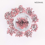 Delicate dried pink flowers arranged around a clear container, perfect for enhancing nail designs with gel polish.