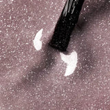 Close-up of Arctic Blush UV gel nail polish with a brush, showcasing its shimmering beige and glitter finish.