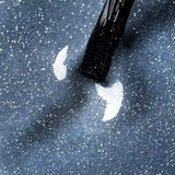 Applying Polar Sparkle UV gel polish with blue cat eye effect on a dark sparkly surface.