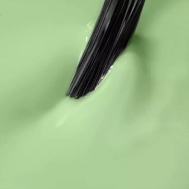 Close-up of black brush dipping into green UV gel polish, ideal for gel nails and home nail kits.