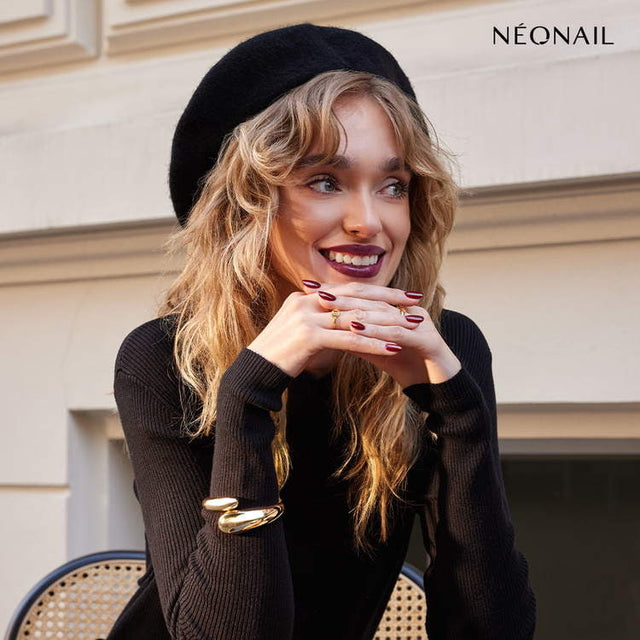 Model showcasing NeoNail burgundy gel nails, wearing a black beret and sweater, exuding autumn vibes.
