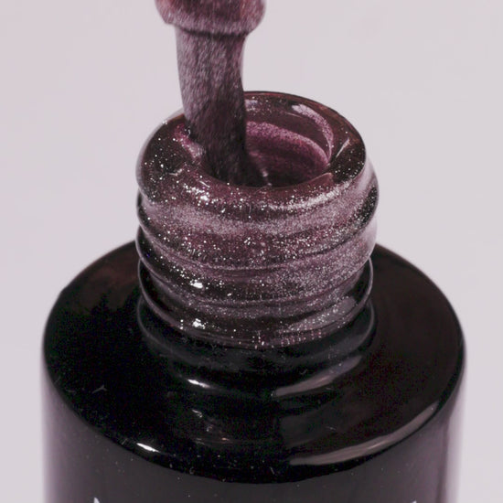 Close-up of Arctic Blush UV gel nail polish bottle showcasing shimmering beige color and brush dipped in gel.