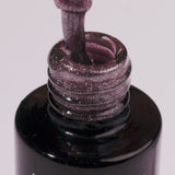 Close-up of Arctic Blush UV gel nail polish bottle showcasing shimmering beige color and brush dipped in gel.