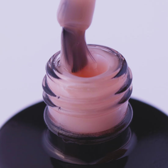 Close-up of Natural Beige expert gel nail polish in a bottle, showcasing its light beige color and smooth consistency.