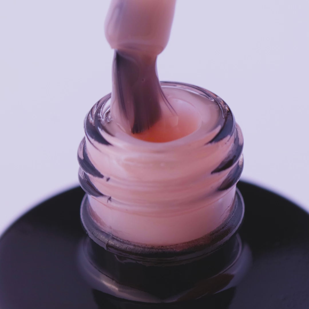 Close-up of Natural Beige expert gel nail polish in a bottle, showcasing its light beige color and smooth consistency.