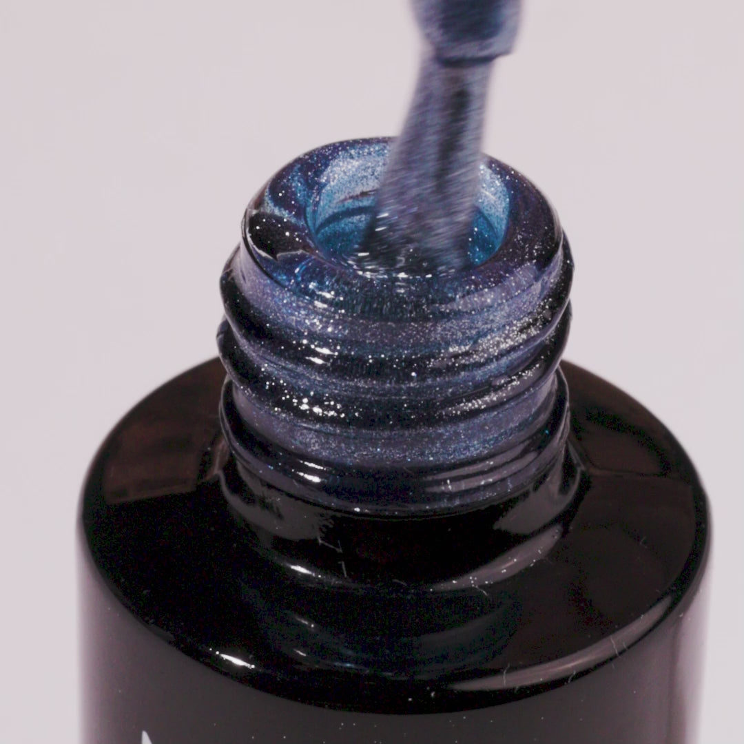 Bottle of Polar Sparkle UV gel nail polish with blue Cat Eye effect spilling out.